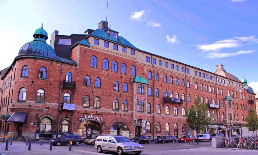 un gran edificio de ladrillo rojo con coches estacionados frente a él en Järnvägshotellet en Gävle