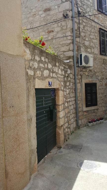 a stone building with a green door with flowers above it at Holiday home Tina in Tribunj