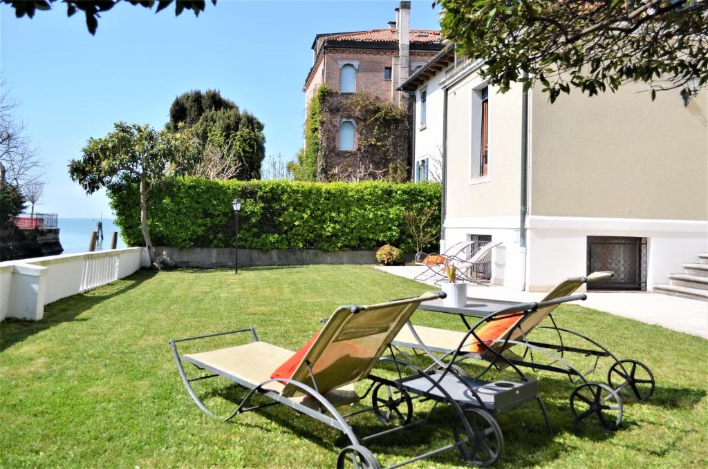 un patio con sillas y una mesa en el césped en Villa Une, garden, beach and culture en Lido de Venecia