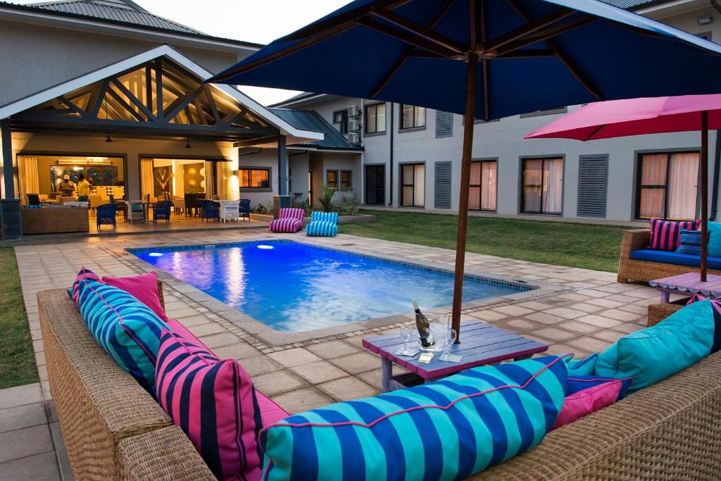 a swimming pool with pillows and an umbrella at The Urban Hotel Ndola in Ndola
