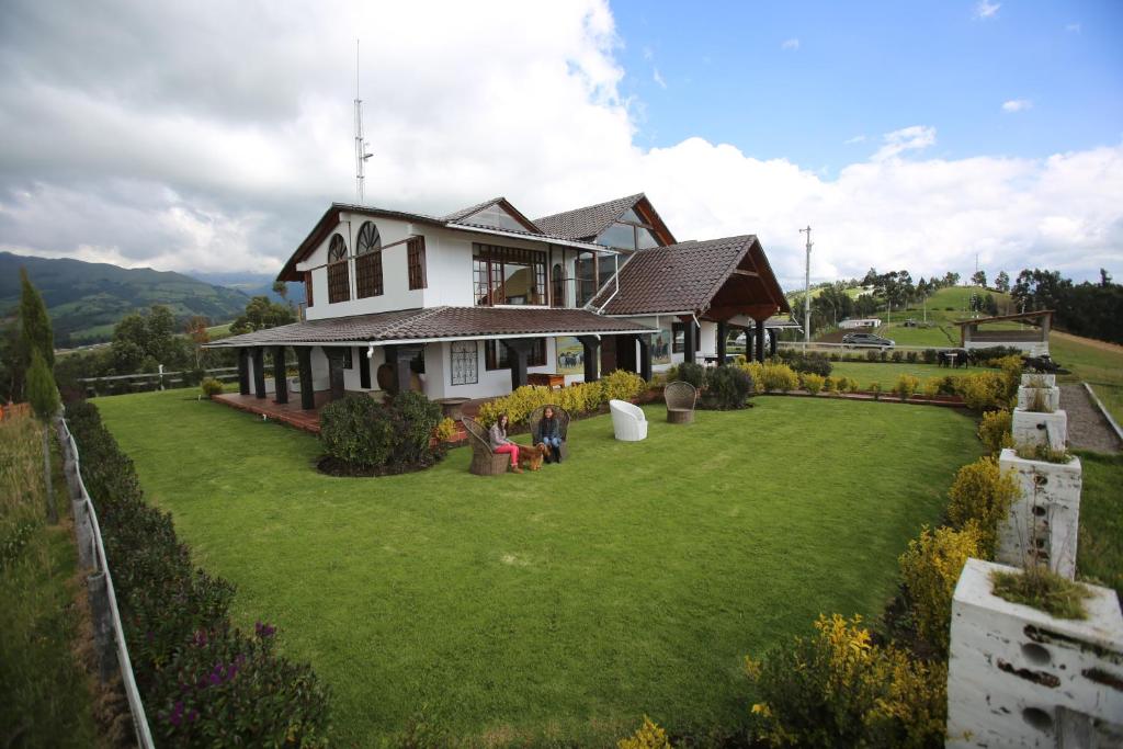a house with a large lawn in front of it at Hosteria Loma Larga Cayambe in Cayambe