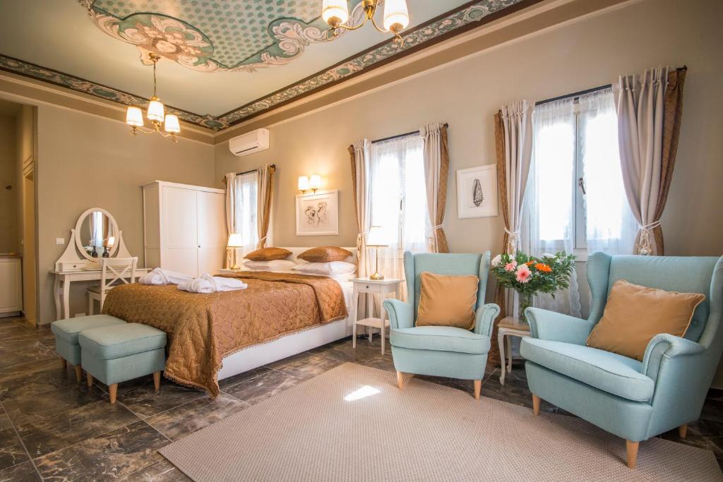 sypialnia z łóżkiem i 2 niebieskimi krzesłami w obiekcie Symi Nautilus Luxury Suites w mieście Simi