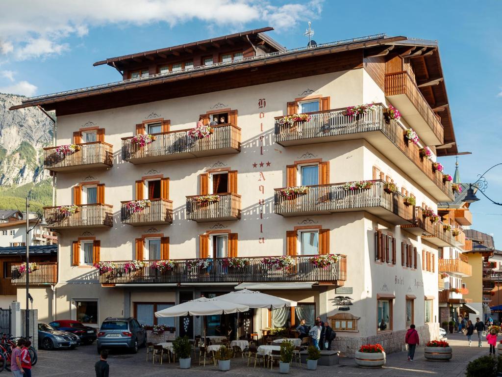 duży budynek z balkonami, stołami i krzesłami w obiekcie Hotel Aquila w mieście Cortina dʼAmpezzo