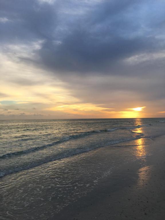 a sunset on a beach with the ocean at Oasis Villa Retreat in Bradenton