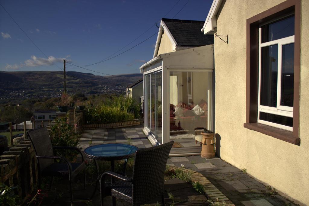 eine Terrasse mit einem Tisch und Stühlen auf einem Haus in der Unterkunft Penybryn Cottages in Aberdare