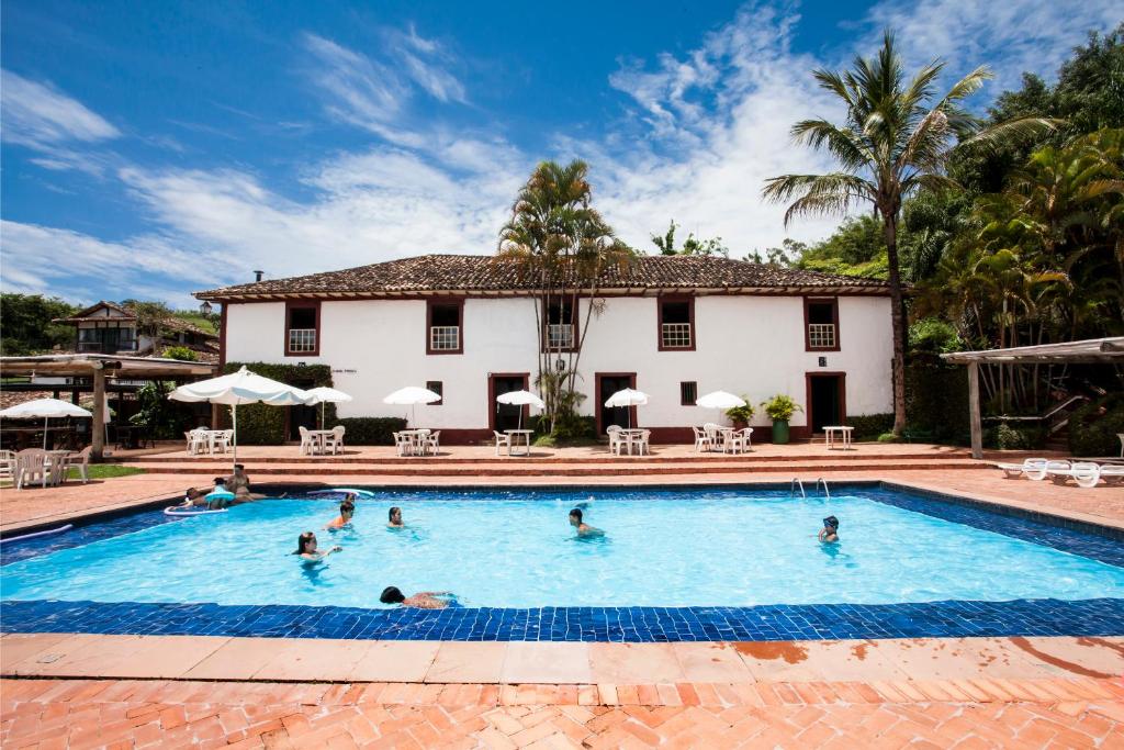 a group of people in a swimming pool in front of a house at Hotel Fazendão in Santa Branca