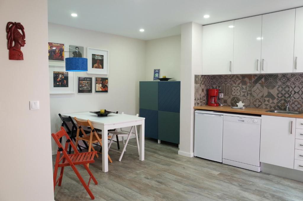 コスタ・ダ・カパリカにあるLisbon Beach Apartments 7の白いキャビネット、テーブルと椅子付きのキッチンが備わります。