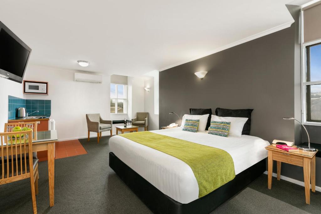 a bedroom with a bed, desk, chair and a lamp at Quest Waterfront in Hobart