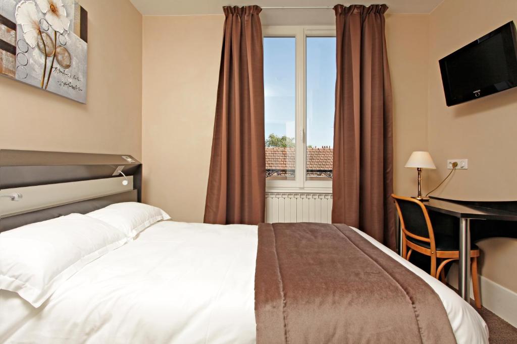 Cette chambre comprend un lit, un bureau et une fenêtre. dans l'établissement Logis Hotel des Bourbons, à Montluçon