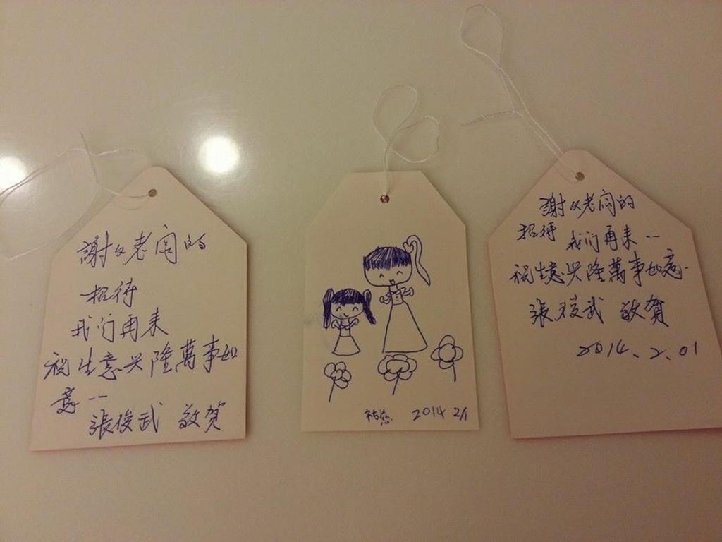 three tags with writing on them on a wall at Park 61 in Luodong