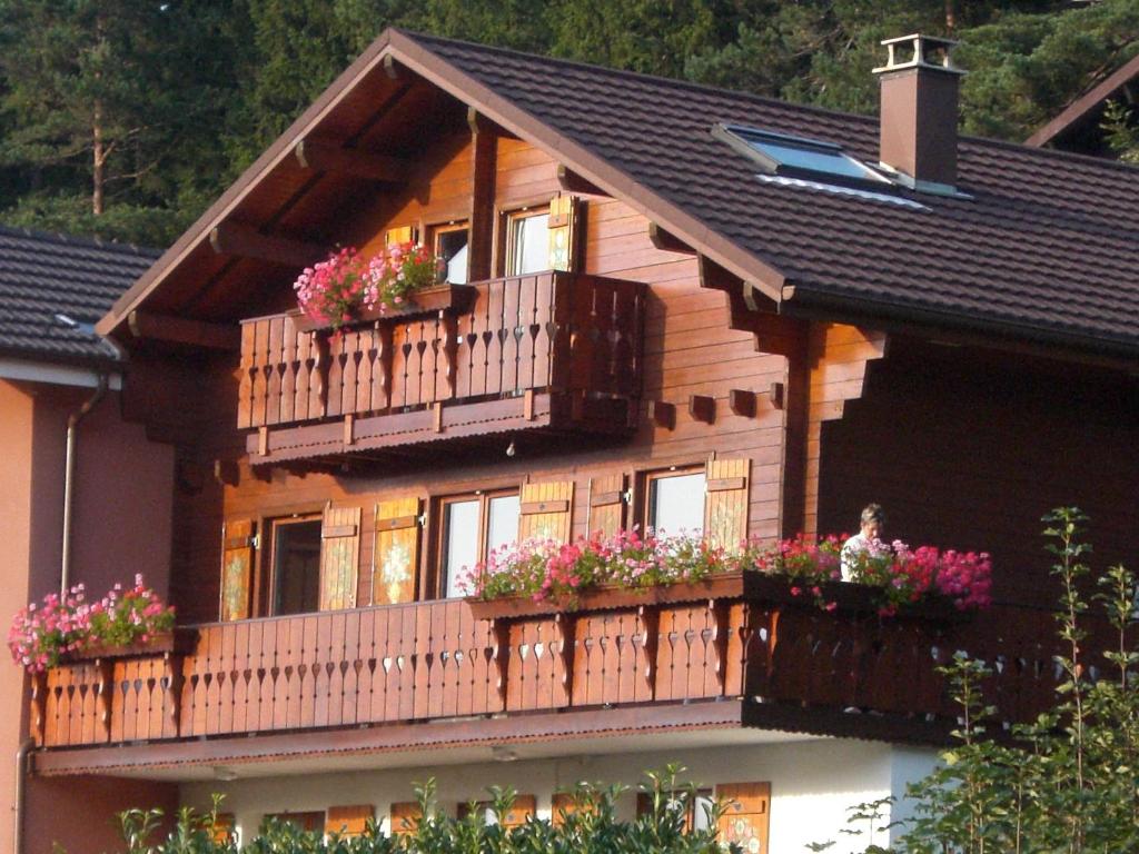 une maison en bois avec des boîtes de fleurs sur son balcon dans l'établissement Appartements 5 Personnes MAYA et LOUNA, à Xonrupt-Longemer