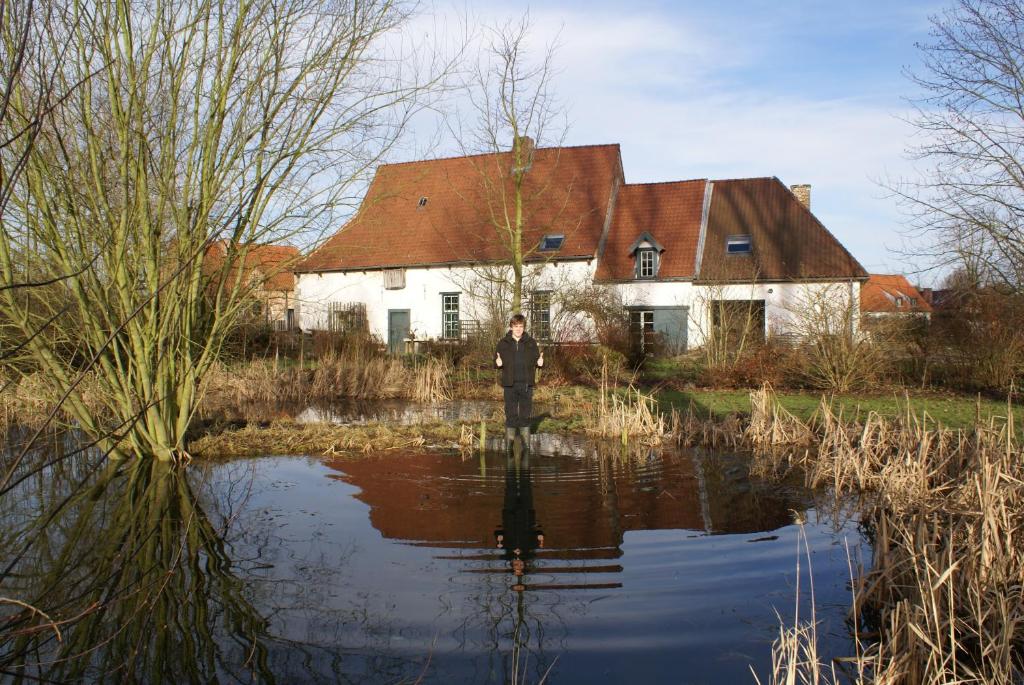 Un uomo in piedi in acqua di fronte a una casa di B&B De Metstermolen a Sint-Truiden