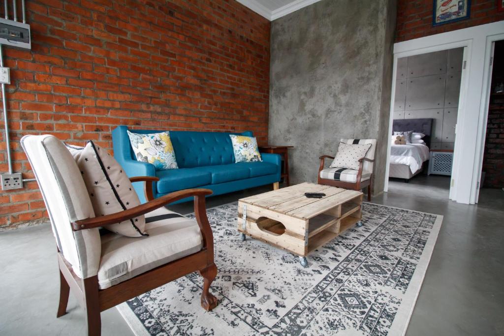 a living room with a blue couch and a coffee table at Rustic Retreat Apartment in Durbanville in Durbanville