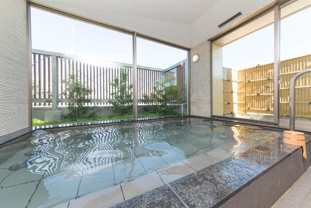 einen Pool in einem Haus mit Glasfenstern in der Unterkunft Sanco Inn Nagoya Nishiki Shikinoyu in Nagoya