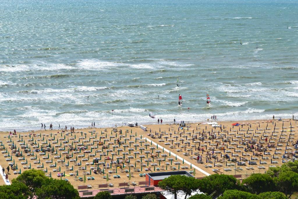 a beach with chairs and people in the ocean at Ariston in Lignano Sabbiadoro