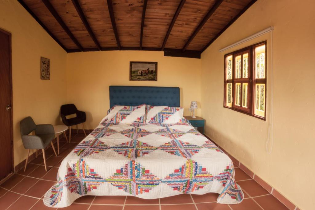 ein Schlafzimmer mit einem Bett mit einer Steppdecke darauf in der Unterkunft La Divina Providencia in Jardin