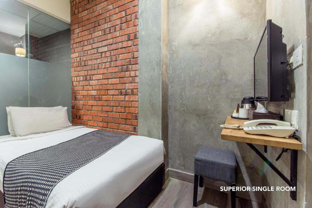 A compact superior single room with a single bed, exposed brick wall and wall-mounted television.