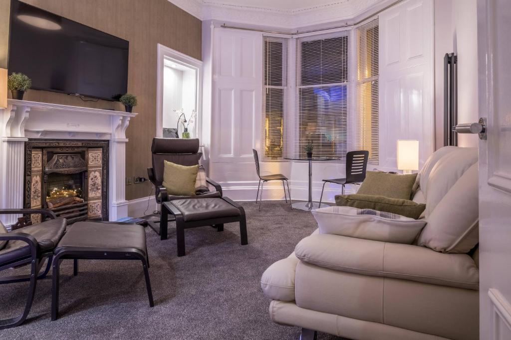 a living room with a couch and a fireplace at West Highland Apartments Milngavie - The Lomond in Milngavie