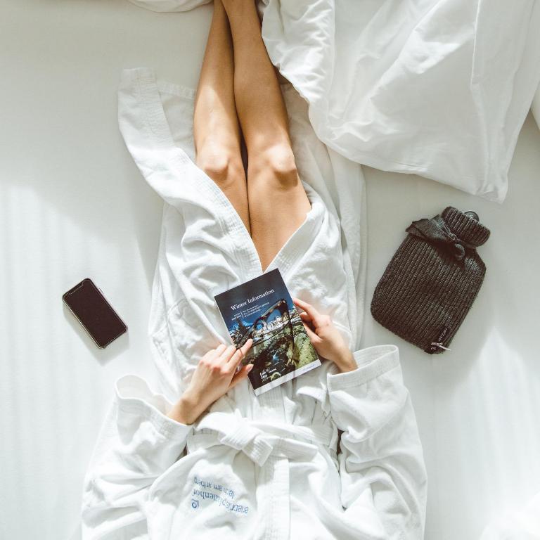 a woman laying on a bed reading a book at Hotel Plattenhof in Lech am Arlberg
