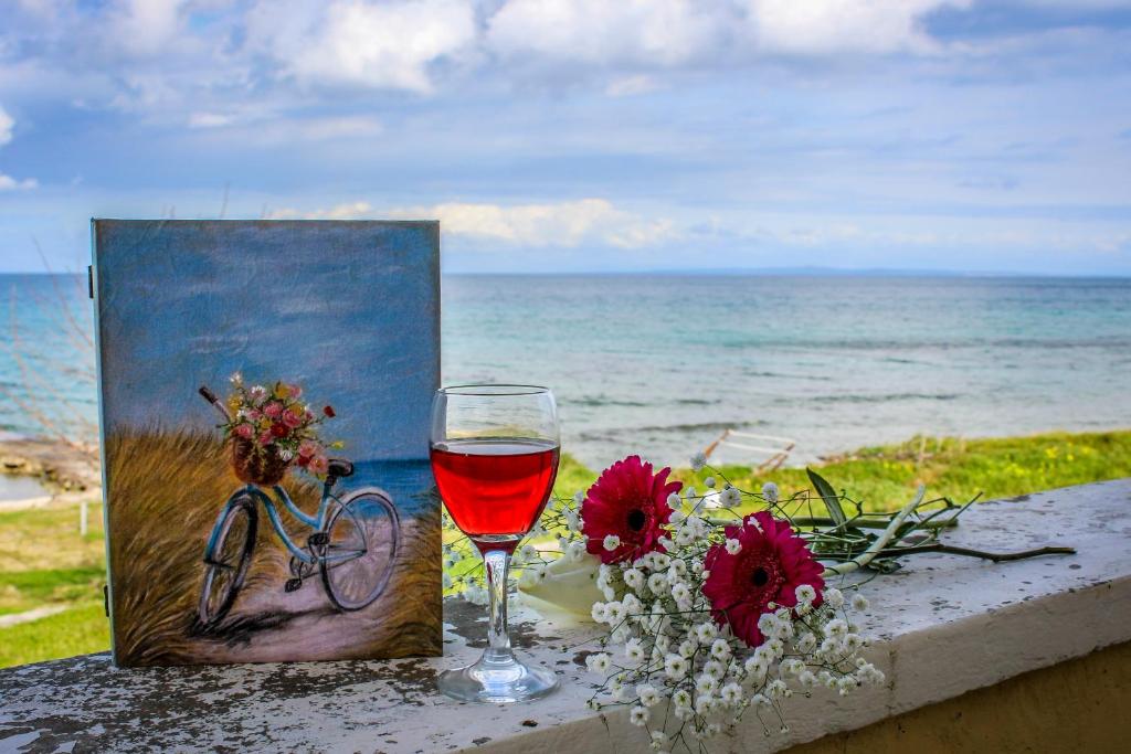 una copa de vino junto a una pintura de una bicicleta en Pelagion II Sea Coral - Beachfront holiday home en Kipseli