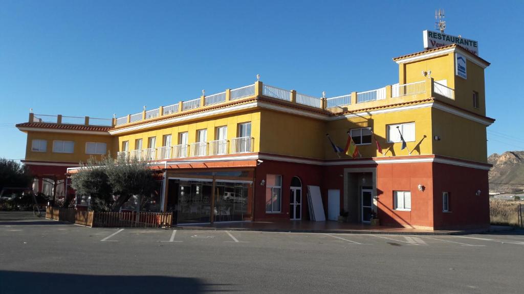 un edificio amarillo y rojo al lado de una calle en Venta de Tébar, en Águilas