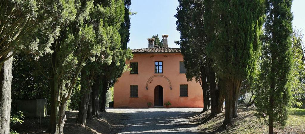 een oranje huis met bomen ervoor bij Villa La Capanna in Montelopio
