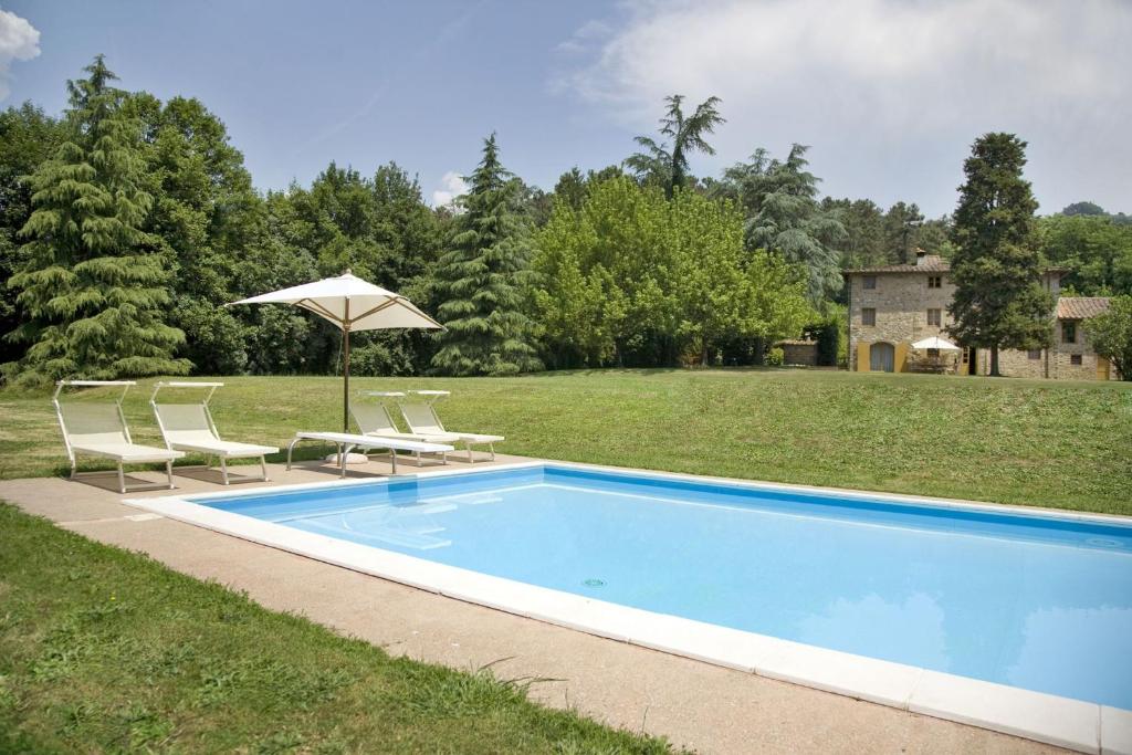 a swimming pool with two chairs and an umbrella at Villa La Cecchella in San Martino in Freddana