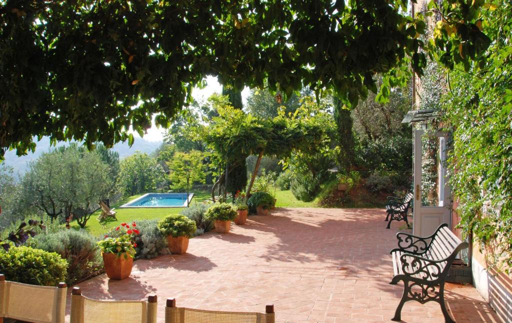 un patio con bancos y plantas y una piscina en Villa La Macchietta, en Monsagrati