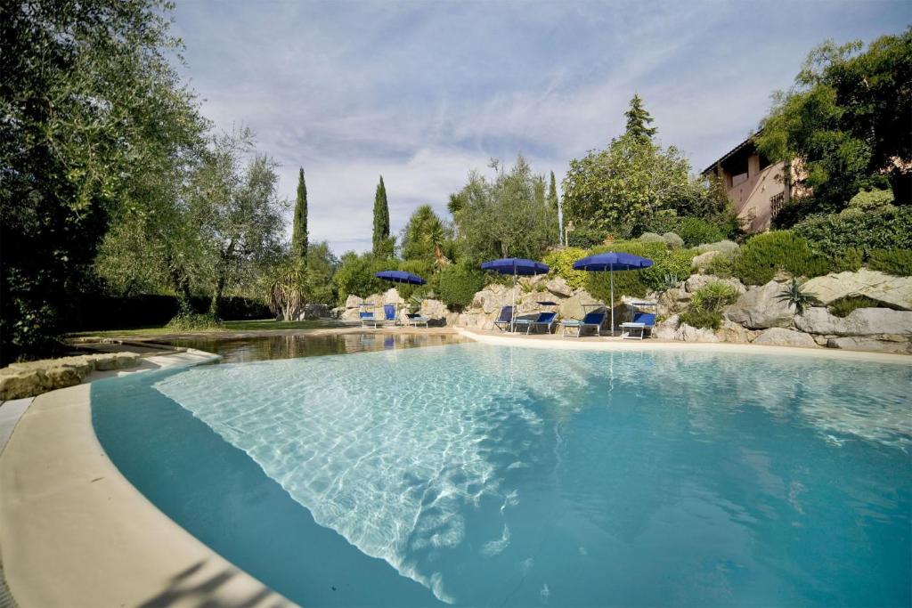 a large swimming pool with chairs and umbrellas at Villa Le Rondini in Montopoli in Val dʼArno