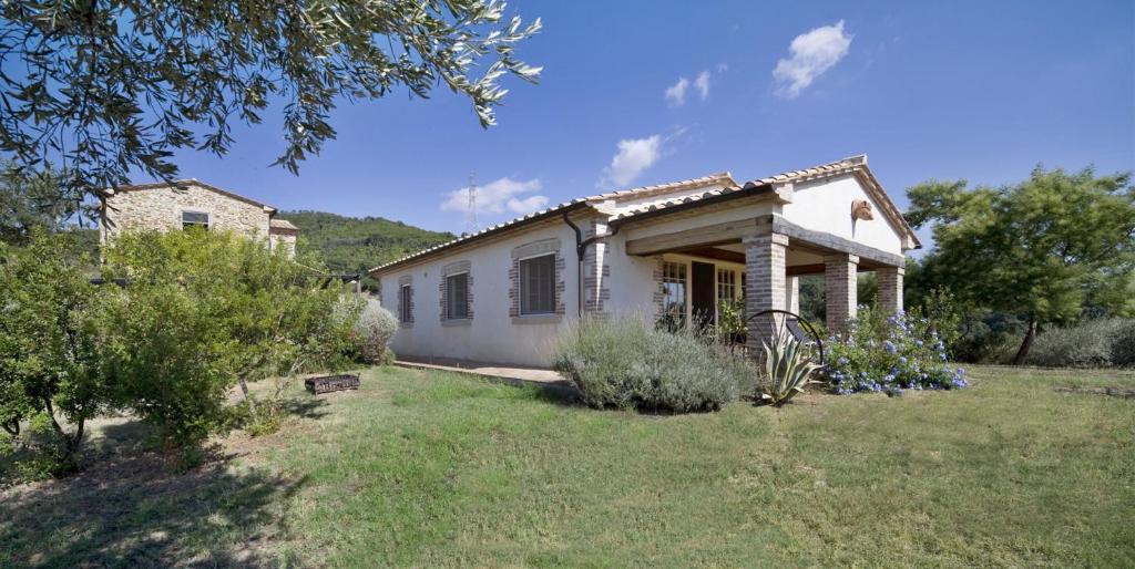 a small white house in the middle of a yard at Villa Santa Barbera in Manciano