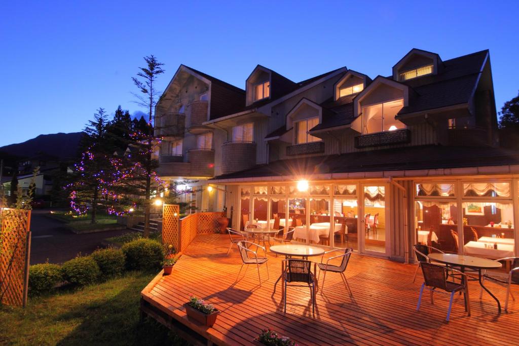 a large house with a deck with tables and chairs at Hotel Natural Garden Nikko in Nikko