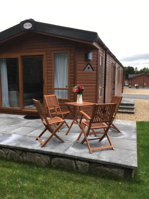 a patio with two chairs and a table in front of a cabin at Shanthi Lodge in Dunning