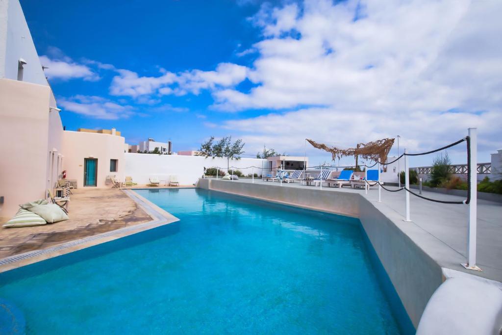 a swimming pool with blue water in a house at Olympic Hotel Santorini in Vóthon