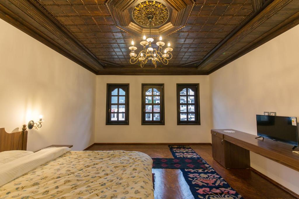 a bedroom with a large bed and a chandelier at Hotel Onufri in Berat