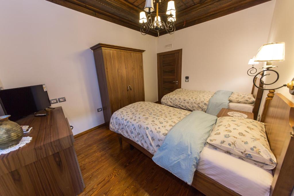 a bedroom with two beds and a desk with a television at Hotel Onufri in Berat