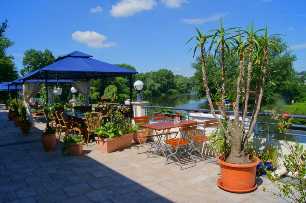 a patio with tables and chairs next to a river at Pension Bootshaus in Weißenfels