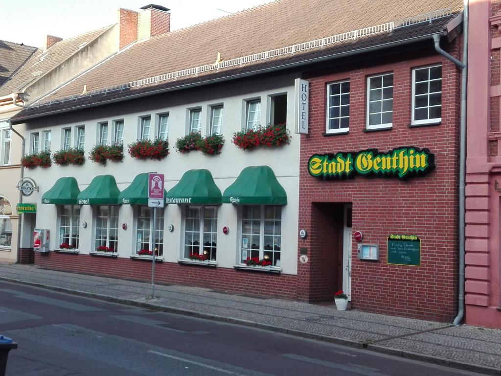 a brick building with green awnings on a street at Hotel & Restaurant Stadt Genthin in Genthin