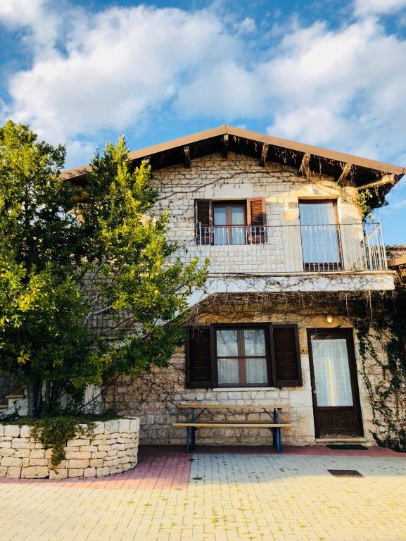 an old stone building with a balcony and a tree at Agriturismo Amicizia in Cassano delle Murge