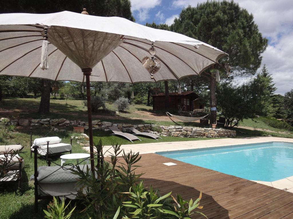 an umbrella and chairs next to a swimming pool at Mas Les Micocouliers in Saint-Christol-lès-Alès