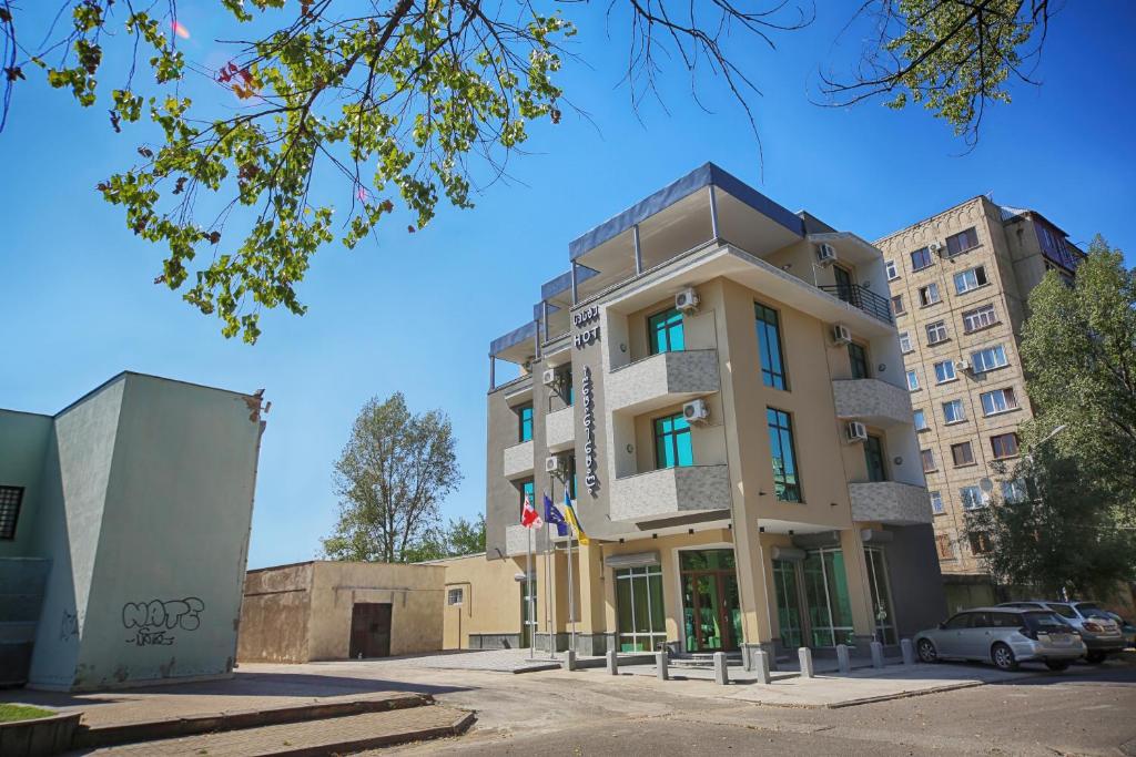 un edificio alto con macchine parcheggiate di fronte di Continental Hotel a Kutaisi