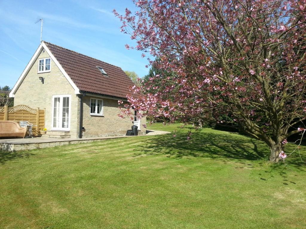 ein Haus mit einem blühenden Baum im Hof in der Unterkunft Waterside Cottage in York