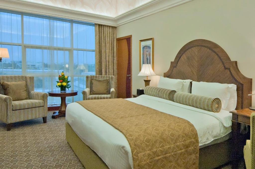 a hotel room with a large bed and a large window at Ayla Hotel in Al Ain