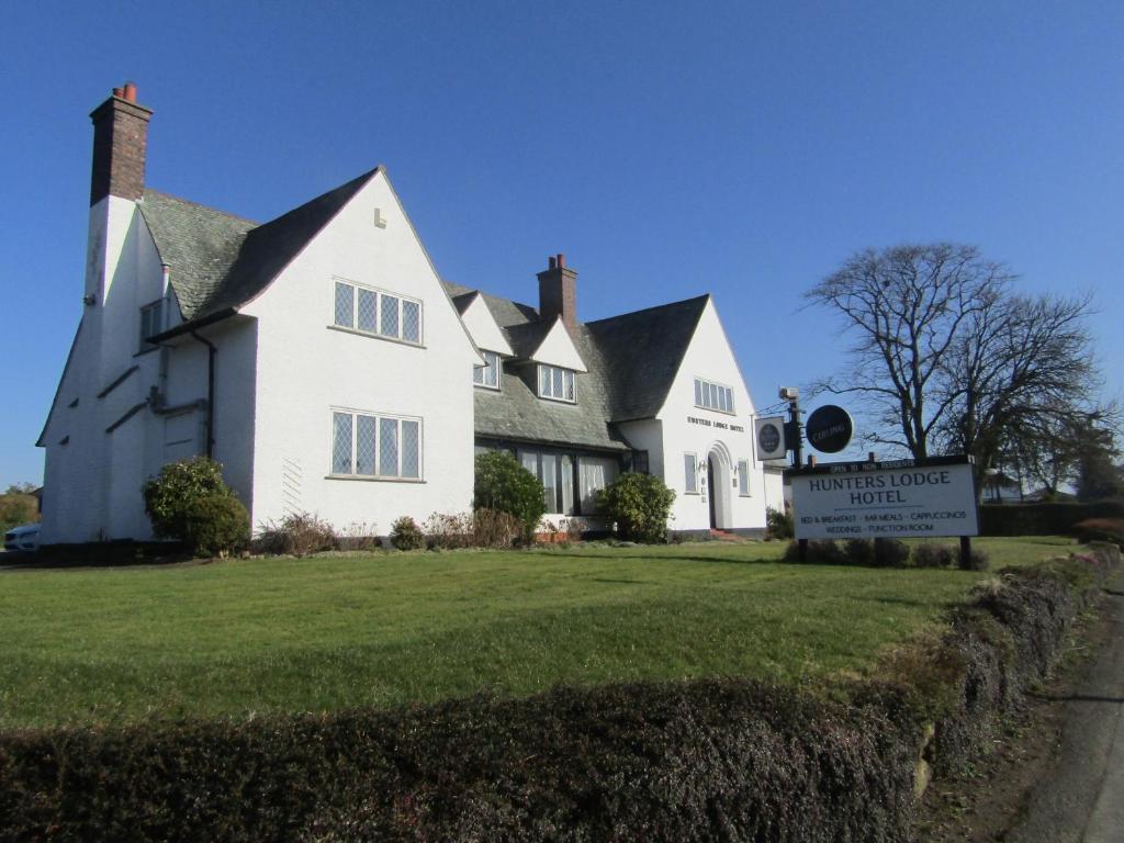 Uma casa branca com um cartaz à frente. em Hunters Lodge Hotel em Gretna Green