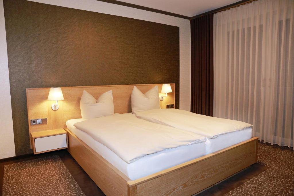 ein Schlafzimmer mit einem großen Bett mit weißer Bettwäsche und Kissen in der Unterkunft Hotel Ratsstuben in Rehden