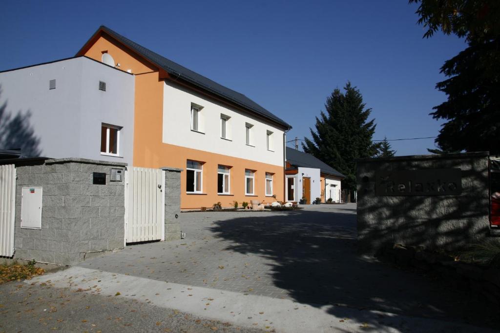 a white and orange building with a fence in front of it at Penzion Relaxko in Fulnek