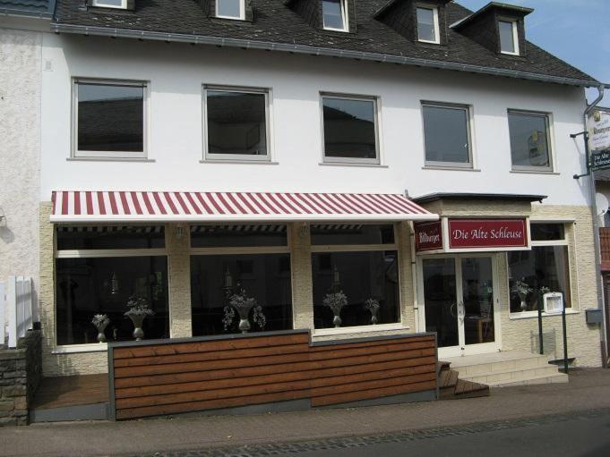 un magasin devant un bâtiment avec un auvent rouge dans l'établissement Herberg Die alte Schleuse, à Manderscheid