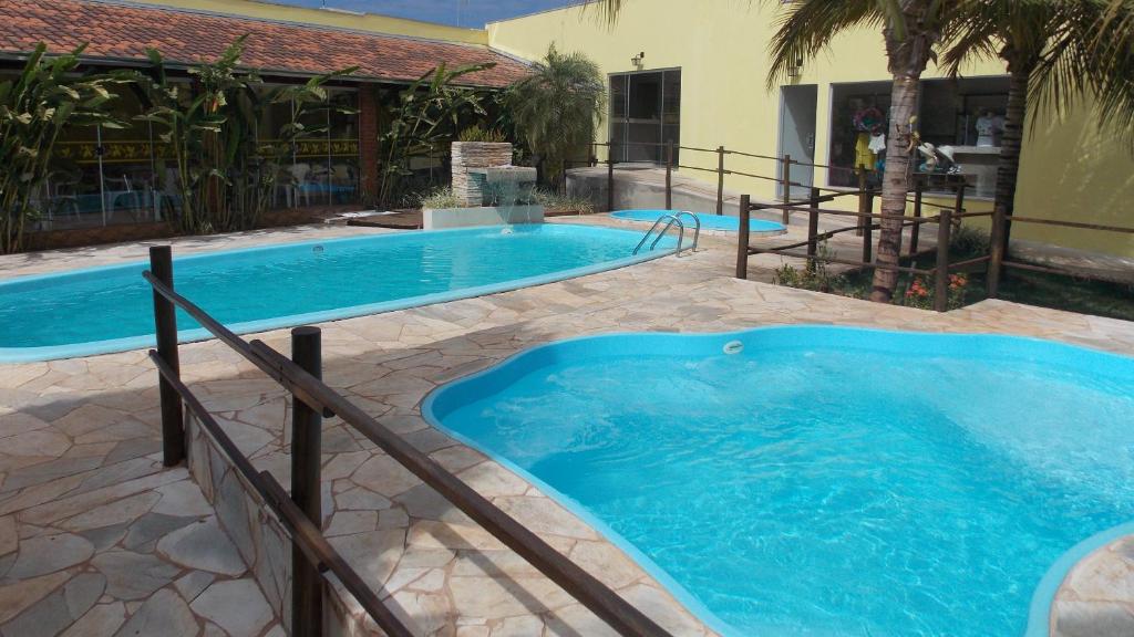 a large swimming pool with blue water in a yard at Pousada Aldeia das Flores in Olímpia