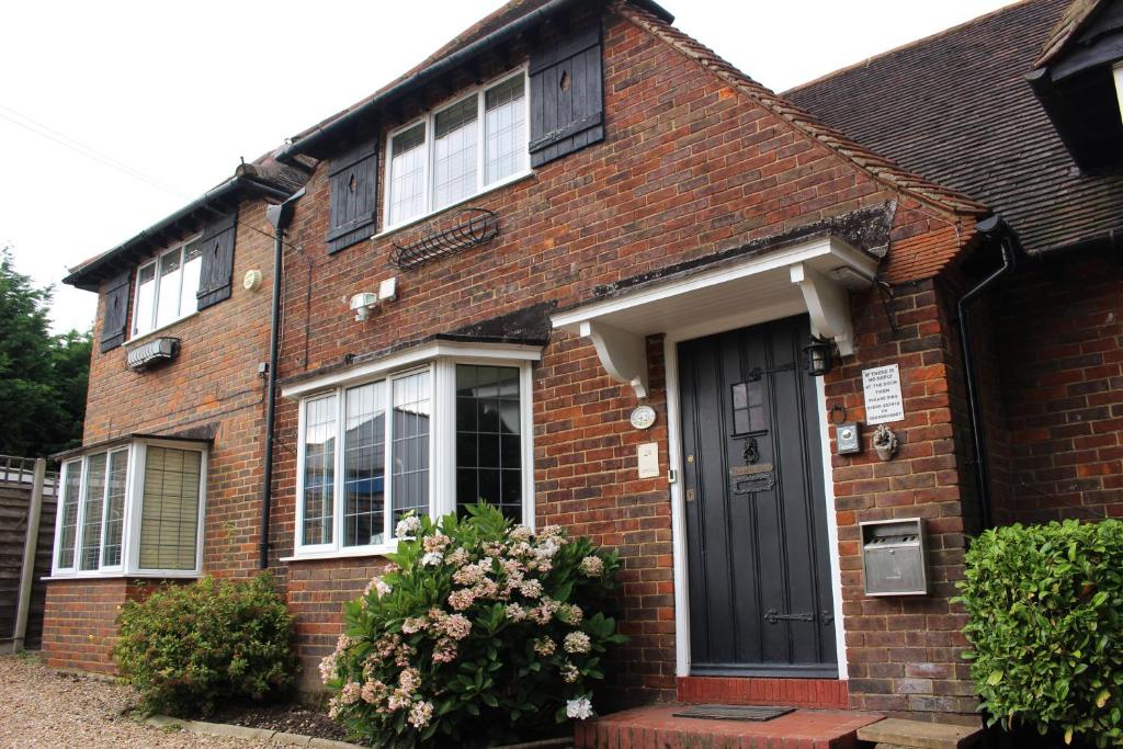 a brick house with a black door and windows at Debden Guest House in Hillingdon