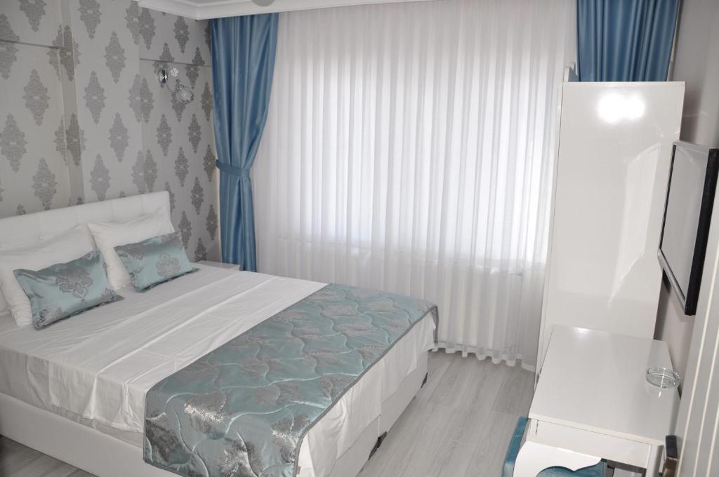 a bedroom with a bed and a window with blue curtains at Hotel Iscen in Mustafakemalpaşa