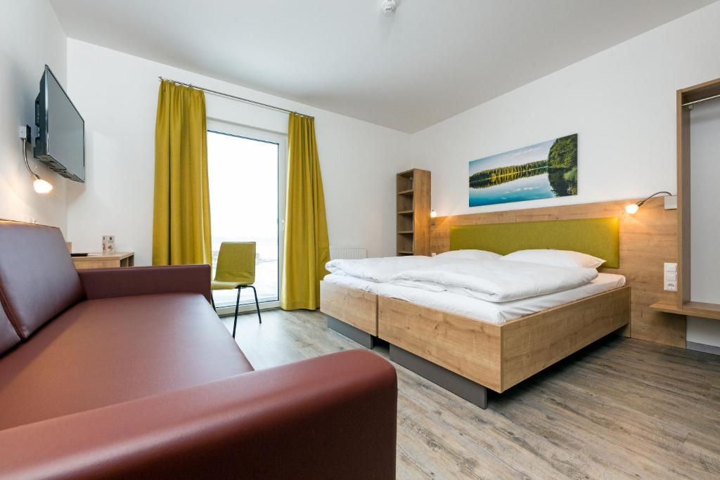 a hotel room with a bed and a couch at Cleverhotel in Herzogenburg